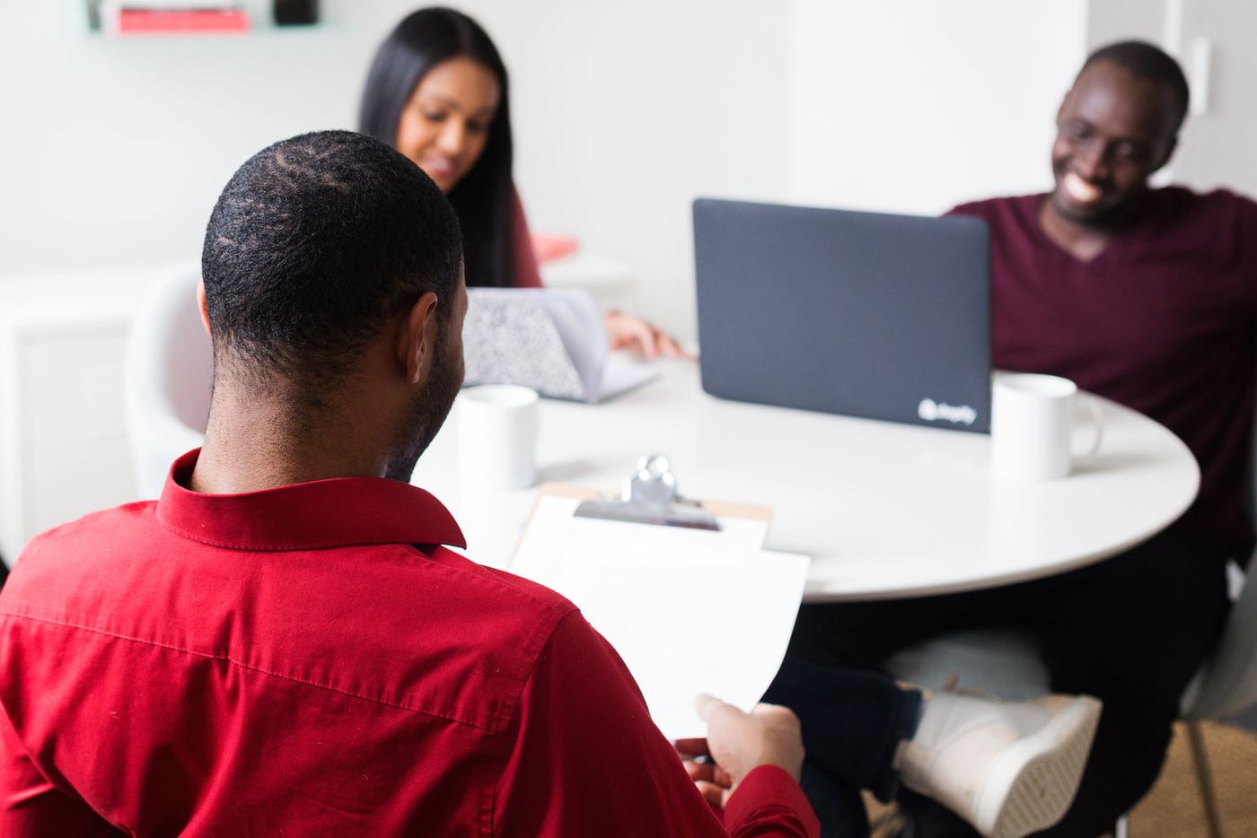 Three people talking around a table with a laptop