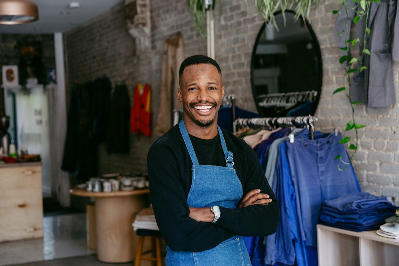 A smiling business owner in a denim apron in his shop